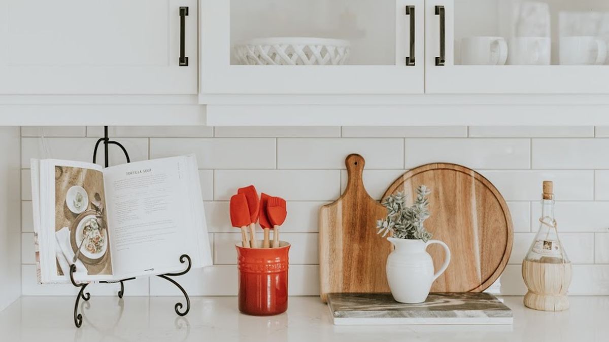 A bright white kitchen counter with shaker cabinetry, wooden boards, and a subway-tile backsplash.